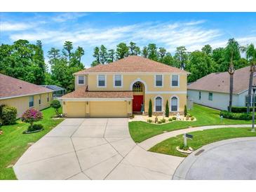 Inviting two-story home boasts a well-manicured lawn, complemented by a three car garage and classic red front door at 21511 Wilderness Lake Blvd, Land O Lakes, FL 34637