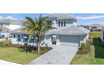 Beautiful two-story home with a paver driveway, lush landscaping, and a modern design at 33759 Ocean Spray Ln, Wesley Chapel, FL 33543