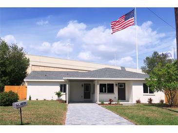 Charming single-story home featuring a manicured lawn, a gray walkway, and a prominent American flag at 4019 W Lemon St, Tampa, FL 33609