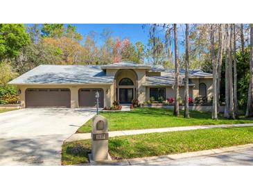 Charming single-story home with a three-car garage, manicured lawn, and beautiful landscaping at 3137 Valemoor Dr, Palm Harbor, FL 34685
