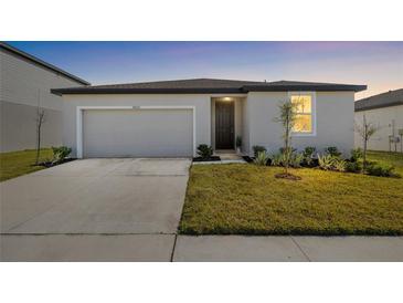 Charming single-story home featuring a two-car garage, manicured lawn, and a welcoming front entrance at 38602 Finn Clover Ln, Zephyrhills, FL 33540