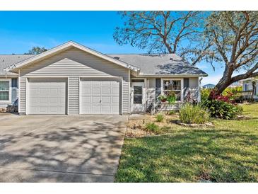 Charming single-story home featuring a two-car garage, landscaped yard, and welcoming front entrance at 39650 Us Highway 19 N # 244, Tarpon Springs, FL 34689