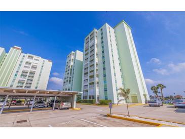 Contemporary condo building featuring covered parking and landscaped grounds against a clear blue sky at 400 64Th Ave # 1108, St Pete Beach, FL 33706