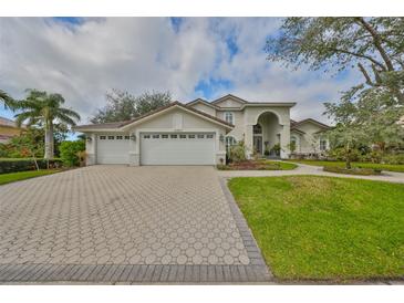 Charming home showcasing a 3-car garage, paved driveway, manicured lawn, and lush landscaping at 6467 Rubia Cir, Apollo Beach, FL 33572