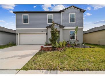 Charming two-story home showcasing a well-manicured lawn and attached two-car garage at 8887 Little Bluestem Dr, Land O Lakes, FL 34637