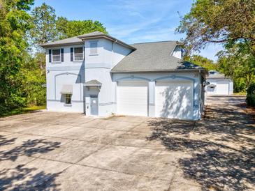 Two-story light-blue home with white garage doors, gray roof, and concrete driveway at 920 E Lake Dr, Tarpon Springs, FL 34688