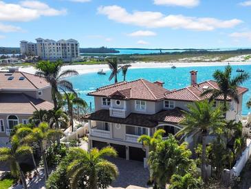 Beautiful waterfront home featuring a tile roof, balcony, mature landscaping, and beachfront access to white sand and turquoise waters at 940 Monte Cristo Blvd, Tierra Verde, FL 33715