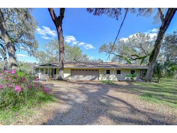 Charming home featuring mature trees, an inviting front porch, and a spacious two-car garage at 13908 Paradise Ln, Dade City, FL 33525