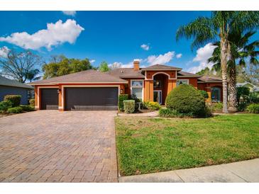 Inviting home featuring a three car garage, brick paver driveway, and well maintained landscaping at 17104 Tiffany Lake Pl, Lutz, FL 33549