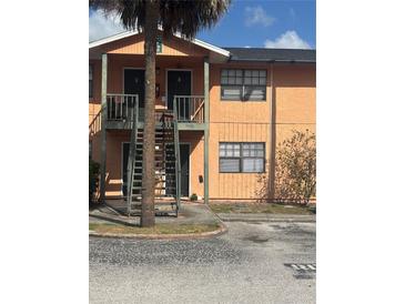 A two-story condo building with an exterior staircase, palm tree, and well-maintained landscaping at 12403 Hibiscus Oak Pl # 202, Tampa, FL 33612