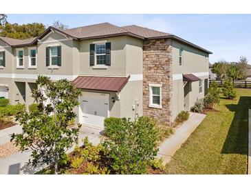 Two-story home features stone accents, neutral color palette, well maintained landscaping, and attached one car garage at 6930 Ripple Pond Loop, Zephyrhills, FL 33541