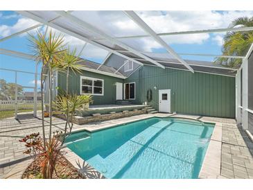 Sparkling pool with a screened enclosure, brick paver patio, and lush landscaping, creating a private backyard oasis at 8759 Orient Ne Way, St Petersburg, FL 33702