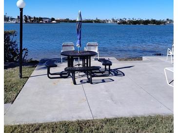 Waterfront picnic area featuring a table, benches, umbrella and chairs along a scenic body of water at 12760 Indian Rocks Rd # 1066, Largo, FL 33774