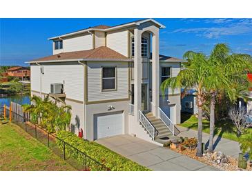 A beautiful two-story home features a garage, landscaped yard with palm trees, and access to a waterfront view at 5100 Cedarbrook, Hernando Beach, FL 34607