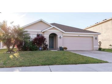 Charming single-story home featuring a well-manicured lawn, a two car garage, and beautiful landscaping at 7771 Davie Ray Dr, Zephyrhills, FL 33540