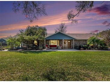 Charming stone home with a welcoming front porch and beautiful landscaping at sunset at 7843 Shoupe Rd, Plant City, FL 33565