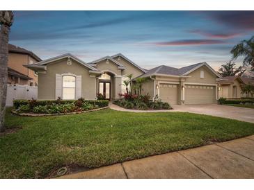 Charming home with a well-manicured lawn, colorful flower beds, and a three-car garage at 1204 Blackrush Dr, Tarpon Springs, FL 34689
