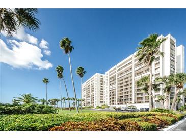 Beautiful beachfront condo building with tropical landscaping and palm trees on a sunny day at 1460 Gulf Blvd # 506, Clearwater Beach, FL 33767