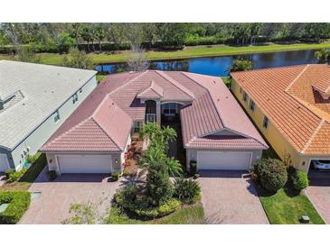 Stunning aerial view of a home with tile roof and mature landscaping near a serene pond at 15728 Aurora Lake Cir, Wimauma, FL 33598