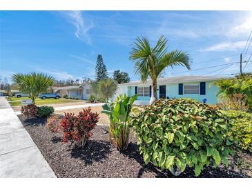 Charming light blue home featuring lush landscaping and a vibrant mix of colorful plants at 3307 Maitland Dr, Holiday, FL 34691