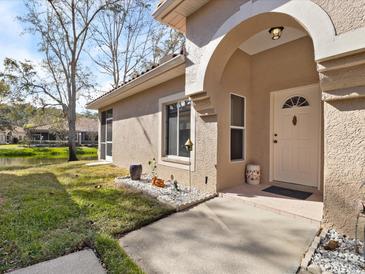 Charming home featuring an arched entrance and well-maintained landscaping near a picturesque pond at 3876 Timber Ridge Ct, Palm Harbor, FL 34685