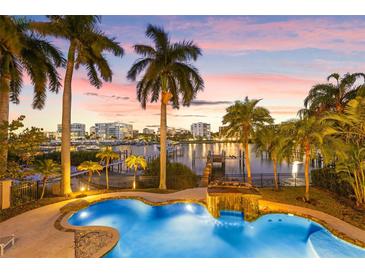 Stunning waterfront pool with lush tropical landscaping and waterfall feature, perfect for relaxation at 436 St Andrews Dr, Belleair, FL 33756