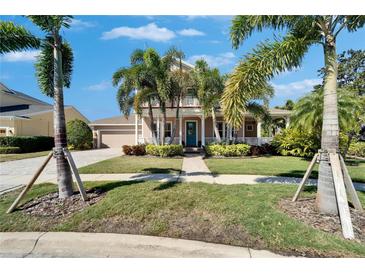 Charming two-story home with a manicured lawn, lush landscaping, and inviting front porch at 5616 Seagrass Pl, Apollo Beach, FL 33572