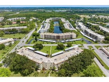 An aerial view of a condo community featuring a central lake, green spaces, and multiple residential buildings at 5750 80Th N St # A106, St Petersburg, FL 33709