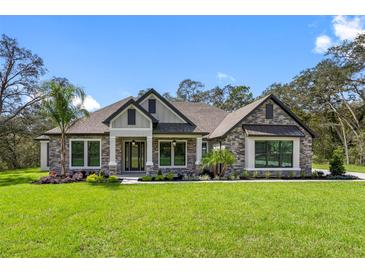 Charming single Gathering home featuring manicured lawn, stone facade, and well-maintained landscaping at 13704 Oldenburg Dr, Hudson, FL 34667