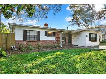 Charming single story home with brick accents, dark shutters, mature landscaping, and a cozy front porch seating area at 3112 S Julia Cir, Tampa, FL 33629