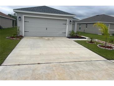 Charming single-Gathering home featuring a gray facade, two-car garage, and well-manicured lawn at 35478 Bellington Blvd, Zephyrhills, FL 33541