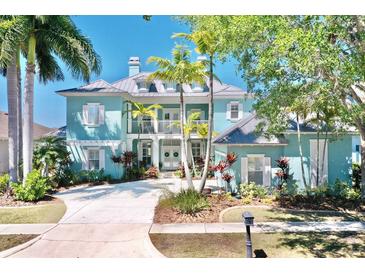 Beautiful light blue two-story home with tropical landscaping and a charming front balcony at 615 Islebay Dr, Apollo Beach, FL 33572