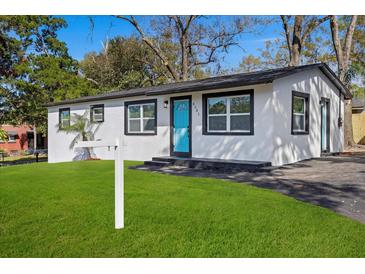 Charming home features a bright blue front door and freshly manicured lawn at 8501 N Alaska St, Tampa, FL 33604
