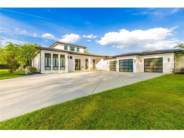 Contemporary home featuring a white exterior, black trim, large driveway, and three-car garage at 5546 Drexel Rd, Land O Lakes, FL 34638