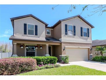 Charming two-story home featuring a manicured lawn, flowering plants, and a welcoming front porch at 2208 Landside Dr, Valrico, FL 33594