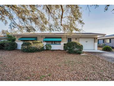 Cozy single-story home featuring teal awnings, attached garage, and landscaped front yard at 2223 Morningside Dr, Clearwater, FL 33764