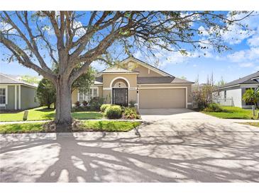 Charming single-Gathering home with an attached two-car garage, mature landscaping, and a cozy front porch at 26944 Affirmed Dr, Wesley Chapel, FL 33544