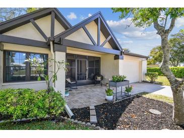 Charming home exterior showcasing a cozy front porch with beautiful landscaping and an attached one car garage at 3462 Sutton Pl, Palm Harbor, FL 34684