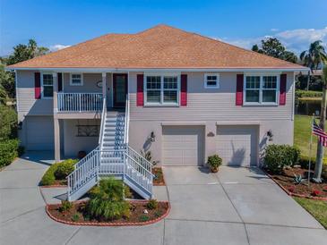 Charming two-story home with a well-manicured lawn, a two-car garage, and front stairs to a landing at 1005 Spoontail Ct, Tarpon Springs, FL 34689