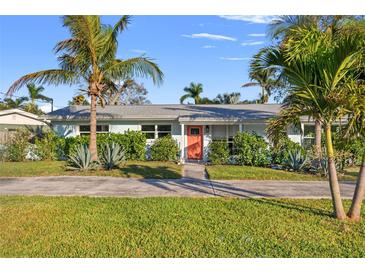 Charming single-story home with lush landscaping, vibrant plants and a welcoming orange front door at 1500 Carson Ne Cir, St Petersburg, FL 33703