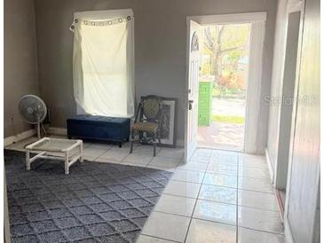 Cozy living room featuring an area rug, window, and doorway leading outside at 2410 Harper St, Tampa, FL 33605