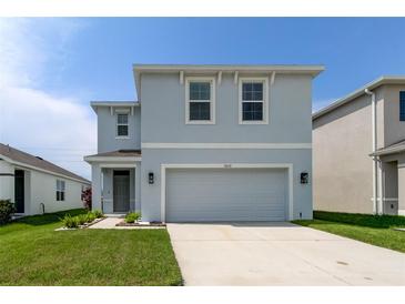 Two-story home with a gray exterior, two-car garage, landscaped front yard, and sidewalk to the front door at 34110 Jasper Stone Dr, Wesley Chapel, FL 33543