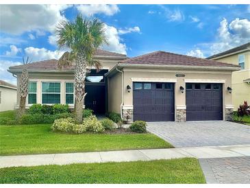 Beautiful single-story home showcasing a well-manicured lawn and three-car garage and detailed roof at 3444 Acacia Bay Ave, Wesley Chapel, FL 33543