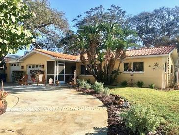 Charming single-story home with a well-maintained lawn and a welcoming brick driveway at 103 Driftwood W Dr, Palm Harbor, FL 34683