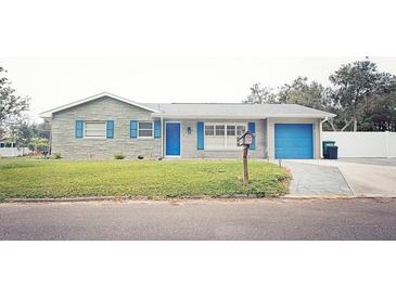 Charming single-story home featuring a stone facade, bright blue shutters and door, and a well-manicured front lawn at 302 N Lauber Way, Tampa, FL 33609