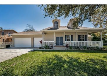 Charming home with a inviting porch, a lush lawn, and a convenient two-car garage at 1028 Rosetree Ln, Tarpon Springs, FL 34689