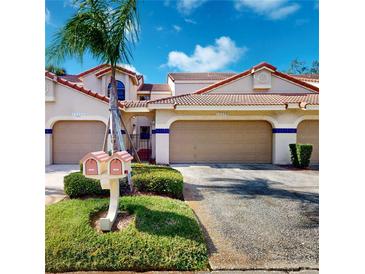 Inviting exterior of a home with a well-maintained lawn, mature palm, and twin mailboxes at 10488 Saint Tropez Pl, Tampa, FL 33615