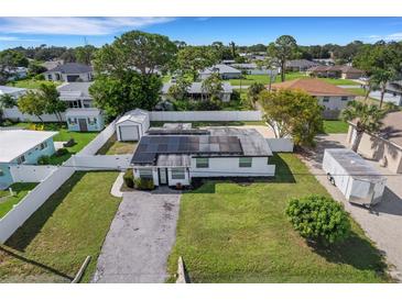 Overhead view of the white home with solar panels, surrounded by a white fence and lush landscaping at 1054 W Baffin Dr, Venice, FL 34293
