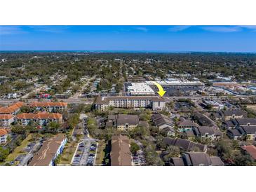 Wide aerial view of a condo complex and surrounding area with trees, roads, and nearby shopping center at 1216 S Missouri Ave # 225, Clearwater, FL 33756