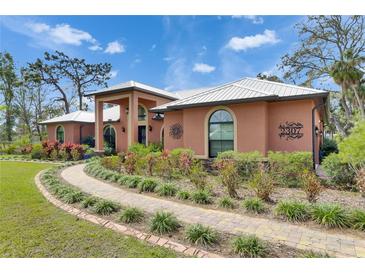 Exterior facade of home showcasing arched windows, professional landscaping, and decorative house numbers at 2307 7Th Sw St, Ruskin, FL 33570